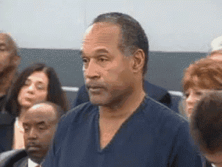 a man in a blue shirt stands in front of a crowd of people .