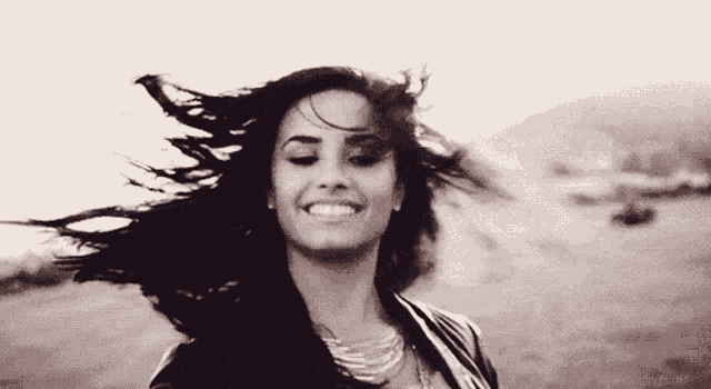 a woman smiles with her hair blowing in the wind