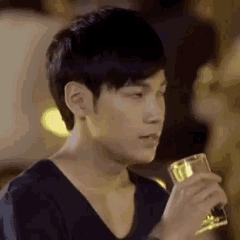 a young man is holding a glass of wine and looking at the camera .