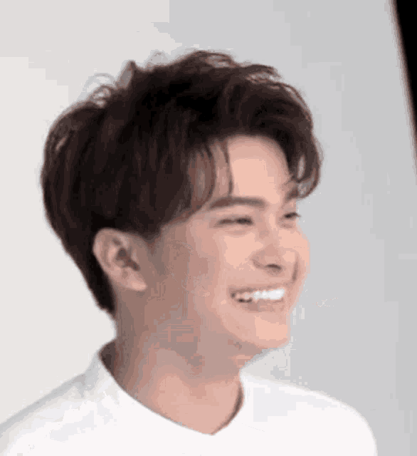 a close up of a man 's face with a white shirt on smiling .