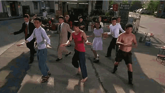 a group of people are dancing on a sidewalk in front of a sign that says ' a ' on it