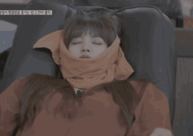 a woman in a red jacket is laying on a chair with a towel wrapped around her head