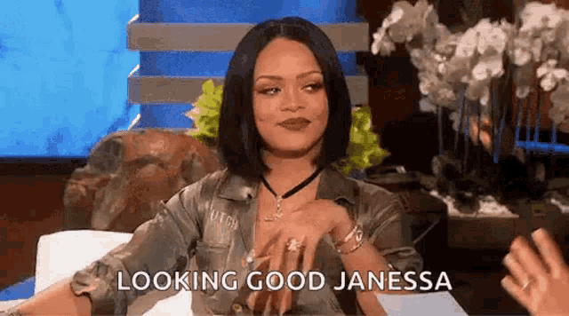 a woman is sitting on a couch talking to another woman while looking good janessa .