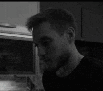 a man with a beard wearing a black shirt is looking down