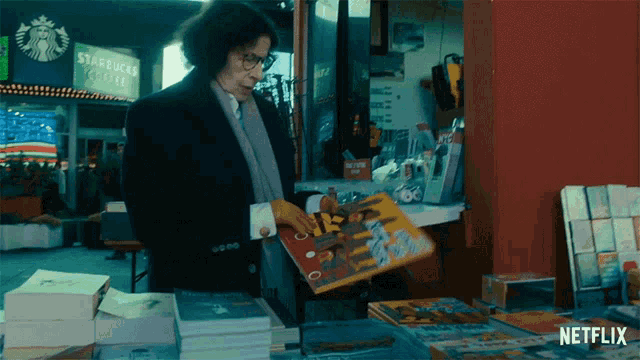 a man holding a book in front of a starbucks coffee shop