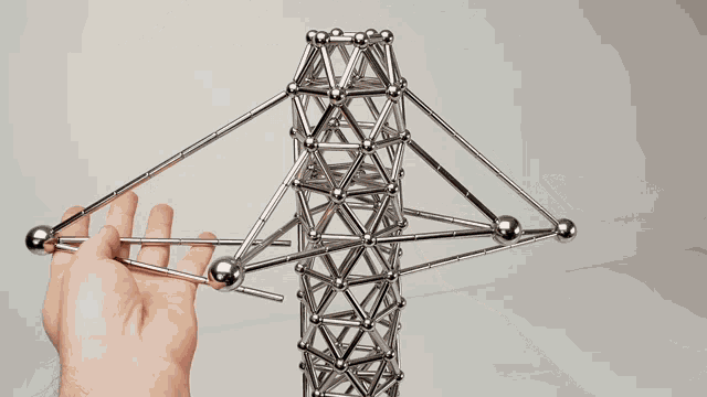 a person is playing with a tower made of metal balls