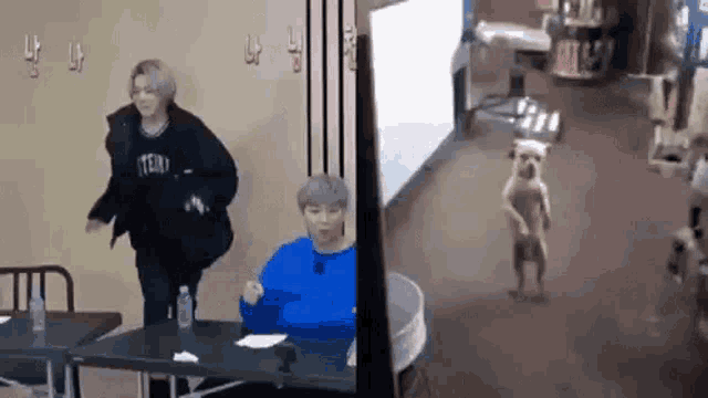a couple of people standing next to each other in a room with a dog standing next to them .