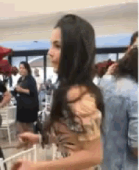 a woman with long dark hair is standing in a crowded room .