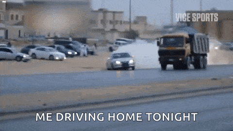 a car is driving down a road next to a dump truck and says `` me driving home tonight '' .