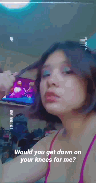 a girl is holding a cell phone and asking would you get down on your knees for me ?
