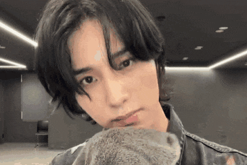 a young man with long black hair is holding a stuffed animal .