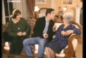 a man and two women are sitting on a couch talking to each other .