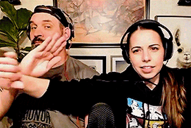 a man and a woman wearing headphones are waving at the camera .