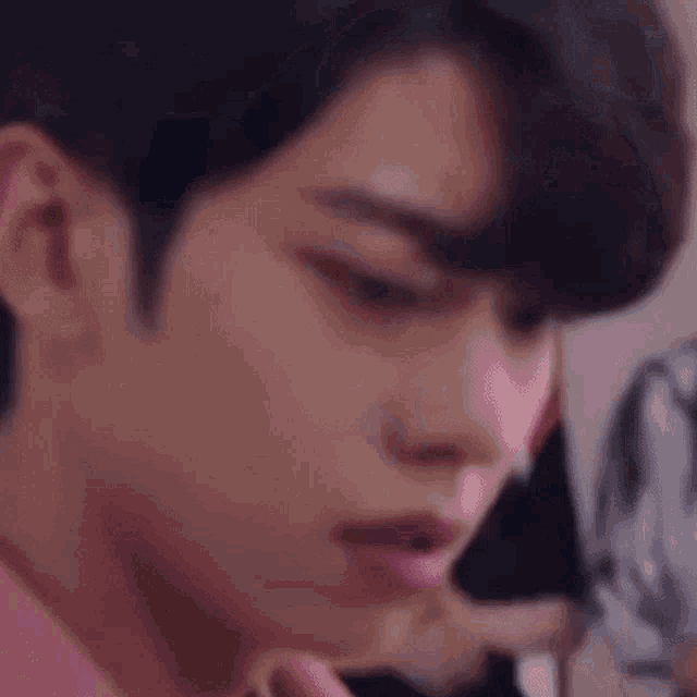 a close up of a young man wearing a pink jacket and a white shirt .