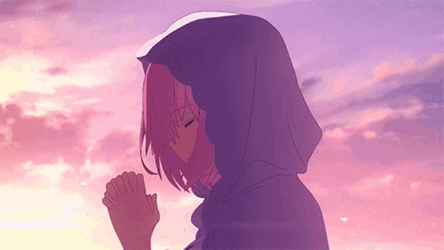 a girl with pink hair is wearing a purple hoodie and praying with her hands folded .
