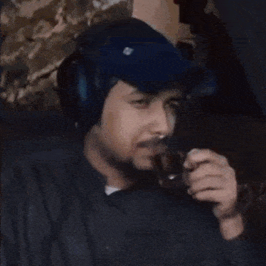 a man wearing headphones is sitting in a chair drinking from a glass .
