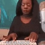 a woman is typing on a keyboard while wearing glasses and a black shirt .
