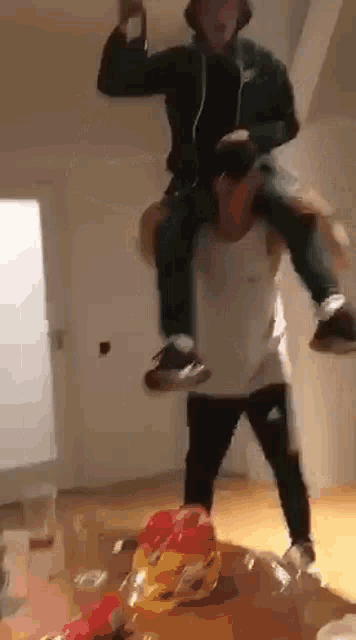 a man is carrying another man on his shoulders while standing on a table .