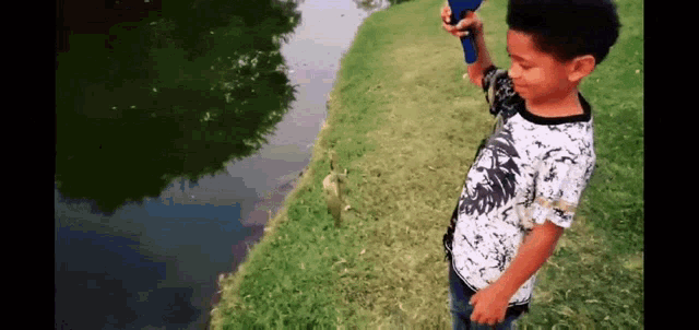 a young boy in a white and black shirt is fishing in a pond