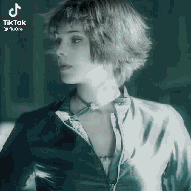 a woman with short hair and a choker is wearing a black jacket and a necklace .