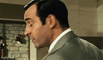 a man in a suit and tie is making a funny face in a kitchen .