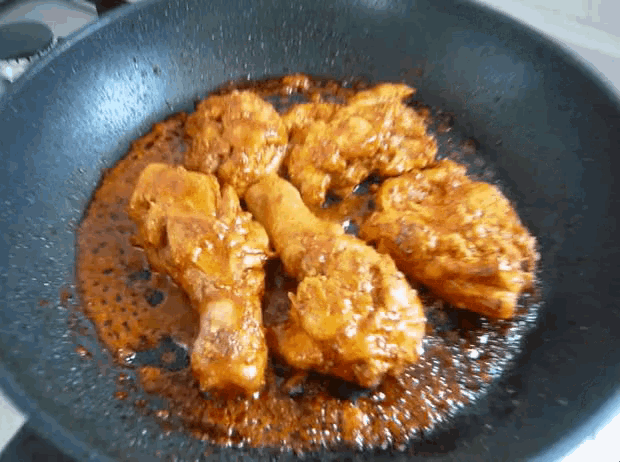 chicken is being cooked in a frying pan