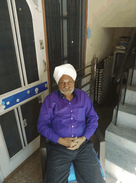 a man in a turban sits in front of a door