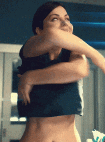 a woman in a crop top is taking off her top