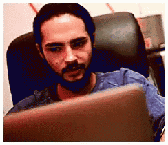 a man with a beard is sitting in front of a laptop computer