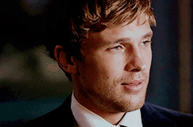 a man in a suit and tie is smiling and looking at the camera