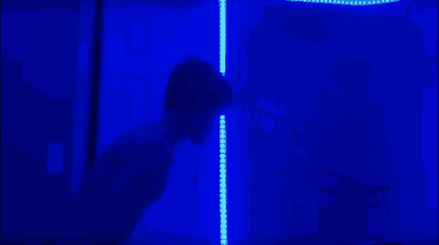 a silhouette of a man standing in front of a blue light