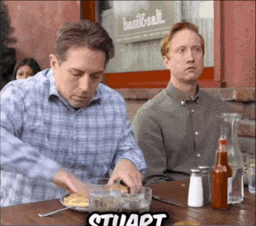 two men are sitting at a table with a sign that says basil & salt