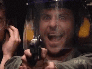 a man wearing a helmet is holding a gun in front of his face