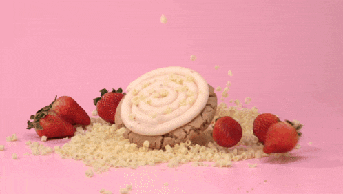a cookie with strawberries in the background and white chocolate chips on it