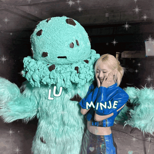 a woman in a blue jacket is standing next to a giant ice cream scoop with the word minje on it