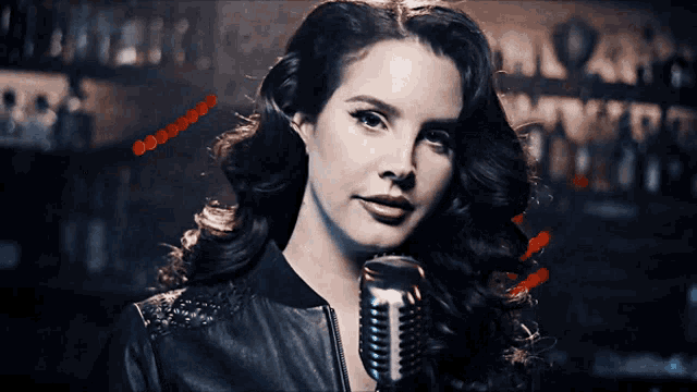 a woman singing into a microphone with a sign in the background that says ' a ' on it