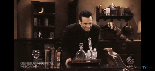 a man in a suit is standing in front of a table that says general hospital on it