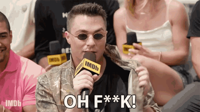 a man holding a microphone that says oh f * * k on it