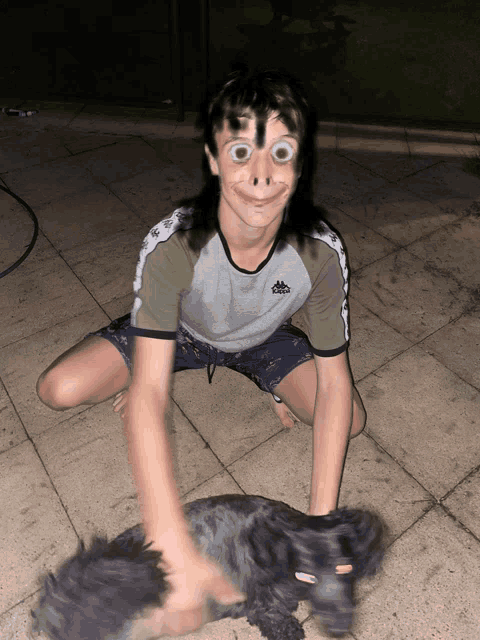 a boy wearing a kappa shirt is kneeling next to a black dog
