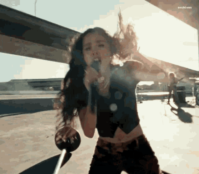 a woman is singing into a microphone while standing on a sidewalk .