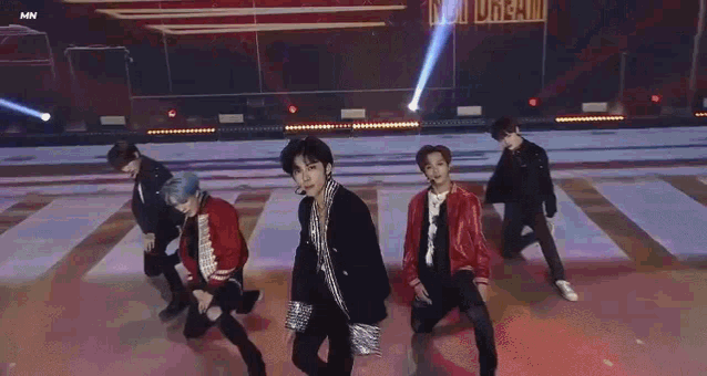 a group of young men are standing on a stage dancing .