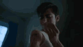 a man in a white tank top is looking at his arm with a needle in it .