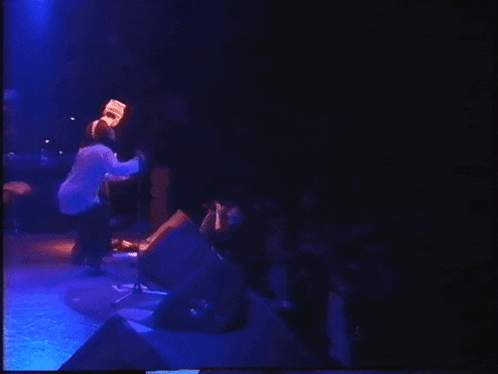 a man in a white shirt is singing into a microphone on a stage