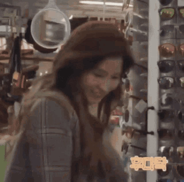a woman is standing in front of a display of sunglasses .