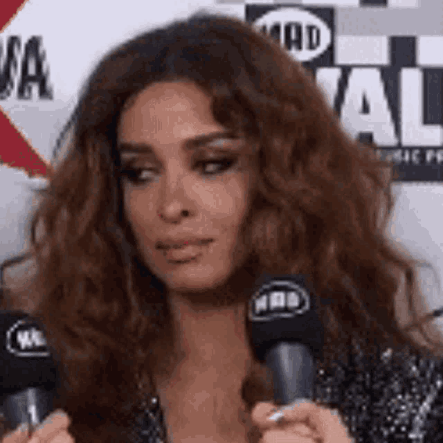 a woman with curly hair is holding two microphones in her hands .