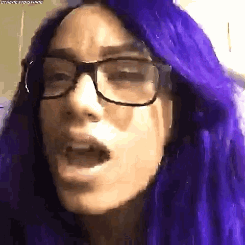 a close up of a woman wearing glasses and purple hair .