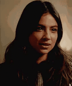a close up of a woman 's face with long dark hair looking at the camera .