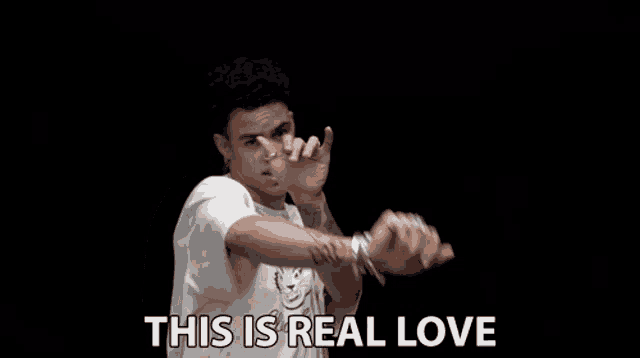 a man in a white shirt is dancing with the words " this is real love " above him