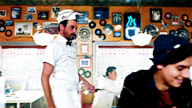 a man in a diner wearing a hat that says ' r.i. ' on it
