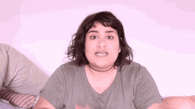 a woman wearing a choker and a t-shirt is laying on a bed .